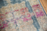 Distressed pile of vintage Oushak rug, revealing fuchsia, denim blue, and beige scrolling vinery.