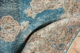 Textured vintage Oushak rug showing faded denim blue and muted beige patterns.