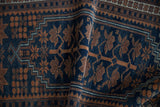 Close-up of a folded Oushak rug, highlighting dusty navy and rust stylized floral patterns.