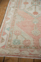 Distressed vintage Oushak runner showcasing pale rose, ivory, and mint geometric motifs.
