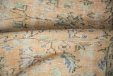 Close-up of distressed Oushak rug's low pile, revealing apricot, seafoam, blue vinery field.