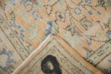 Distressed Oushak rug fold revealing worn pile, subtle colors, and painted number on reverse.