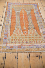 Worn pale orange field and lavender border on a distressed vintage Oushak rug.