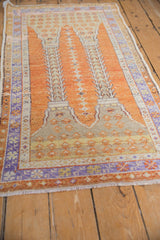 Distressed vintage Oushak rug showing pale orange field, purple floral border, knot wear.