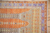 Corner detail of vintage distressed Oushak rug, showing pale orange, lavender floral, and sand patterns.