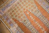 Distressed Vintage Oushak rug edge with pale orange, sand, and lavender pattern details.