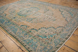 Distressed vintage Oushak carpet with faded turquoise arabesque border and floral blossoms.