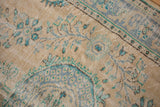 Distressed vintage Oushak rug, beige pile with faded blue floral blossoms and even wear.