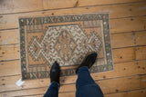 Distressed Oushak rug's geometric medallion in ivory, sandalwood, and oxidized silver.