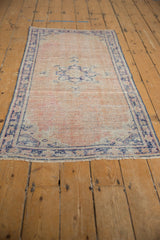 Distressed Oushak runner pile in dusty rose with cobalt blue border and visible wear.