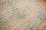 Detail of distressed vintage Oushak rug, showing faded denim blue motifs on worn beige pile.