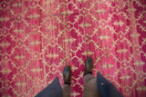 Distressed Oushak rug with fuchsia ground, ivory germinating buds, and trellis pattern underfoot.