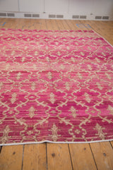 Heavily abrashed fuchsia ground of a distressed vintage Oushak, showing ivory trellis and buds.