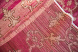 Distressed Oushak carpet reverse, revealing raspberry and ivory hand-knotted foundation.