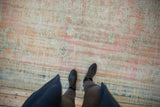 Vintage distressed Oushak carpet showcasing faded blush, apricot, pale blue, and visible wear.