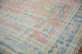 Distressed Oushak carpet with faded blush, apricot, and pale blue Rococo arabesques.