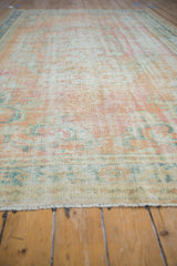 Distressed Oushak rug, showing worn pile, diffused arabesque patterns, and blush, apricot hues.