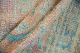 Distressed Oushak rug texture with worn pile revealing blush, apricot, and denim blue.