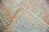 Distressed Oushak rug detail: worn pile, blush and blue tones, side cord, and fringe.