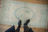 Distressed Oushak runner underfoot, showing faded seafoam green medallion on ivory pile.