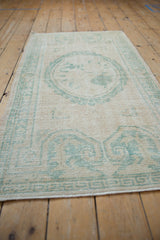Textured low pile of vintage distressed Oushak rug, seafoam green cameo floral design on ivory.