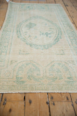 Distressed vintage Oushak runner with decorative wear, ivory pile revealing foundation and seafoam patterns.