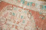 Distressed texture of vintage Oushak rug with cinnabar red, turquoise, and beige floral patterns.