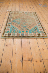 Distressed Oushak rug corner, showing its traditional geometric border in pale coffee, turquoise, and chocolate.
