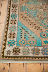 Distressed hand-knotted Oushak rug corner detail with turquoise, beige, and chocolate brown motifs.