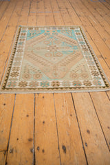 Distressed Oushak rug corner, beige, turquoise floral border, and shallow, even pile.