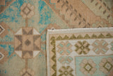 Vintage distressed Oushak rug showing intact selvage, wear on knot heads, turquoise and beige tones.