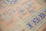 Distressed Oushak carpet close-up, showing apricot field with blue floral sprays and worn cobalt border.