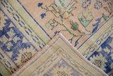 Distressed apricot Oushak rug corner showing blue border abrashes and woven back.