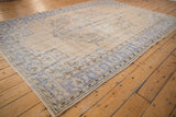 Faded royal blue, mint green border, and beige field on a distressed Oushak corner.