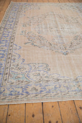 Vintage distressed Oushak rug with faded royal blue floral motifs and textured wear.