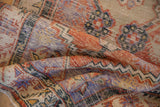 Distressed texture of vintage Oushak rug with muted brick red, blue, and ivory patterns.