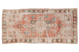 Distressed vintage Oushak runner rug with faded cherry red, ivory, turquoise floral medallion.