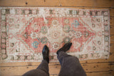 Overhead view of a distressed Oushak runner with faded red, ivory, turquoise, charcoal patterns.
