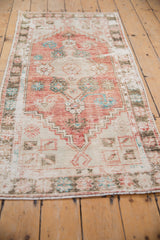 Distressed Oushak runner showcasing faded cherry red, ivory, turquoise floral medallion and worn pile.