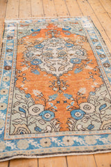 Distressed terra cotta field with sky blue floral motifs on a vintage Oushak rug.