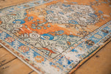 Distressed Oushak rug: terra cotta, sapphire blue floral details, worn texture, and intact selvage.