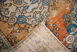 Distressed terra cotta and ivory Oushak pile, revealing floral patterns and woven back.