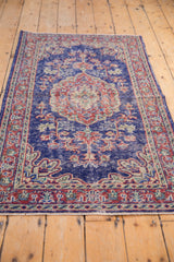 Worn distressed Oushak rug border and field, showcasing cobalt blue, cherry red, and ivory patterns.
