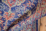 Folded detail of distressed Oushak rug, showing worn cobalt blue vinery motifs.