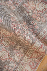 Distressed Sparta rug's worn texture, visible foundation, and faded cherry red floral pattern.