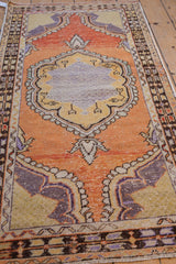 Distressed tangerine orange field with scalloped aubergine and saffron medallion of vintage Oushak rug.