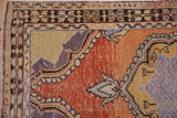 Distressed Oushak rug corner, scalloped medallion, geometric border, tangerine orange, saffron yellow, aubergine.