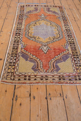 Distressed Oushak runner with scalloped medallion, vibrant tangerine, saffron, and aubergine tones.