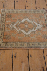 Distressed Oushak corner with terracotta and ivory starbursts, showing low pile and intact selvage.