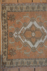 Distressed Oushak rug corner detail, terracotta field, ivory patterns, and a fringed border.